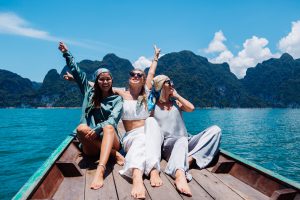 three-woman-tourists-friends-travel-around-khao-sok-national-park-vacation-thailand-sailing-asian-boat-lake-sunny-day-with-amazing-view